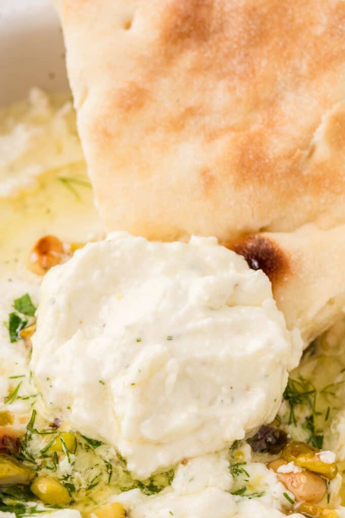 a closeup photo of a piece of toasted pita bread with a generous helping of creamy feta dip