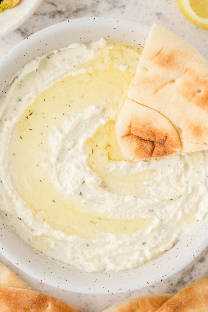 ungarnished whipped feta dip, with a slice of toasted pita ready to be eaten