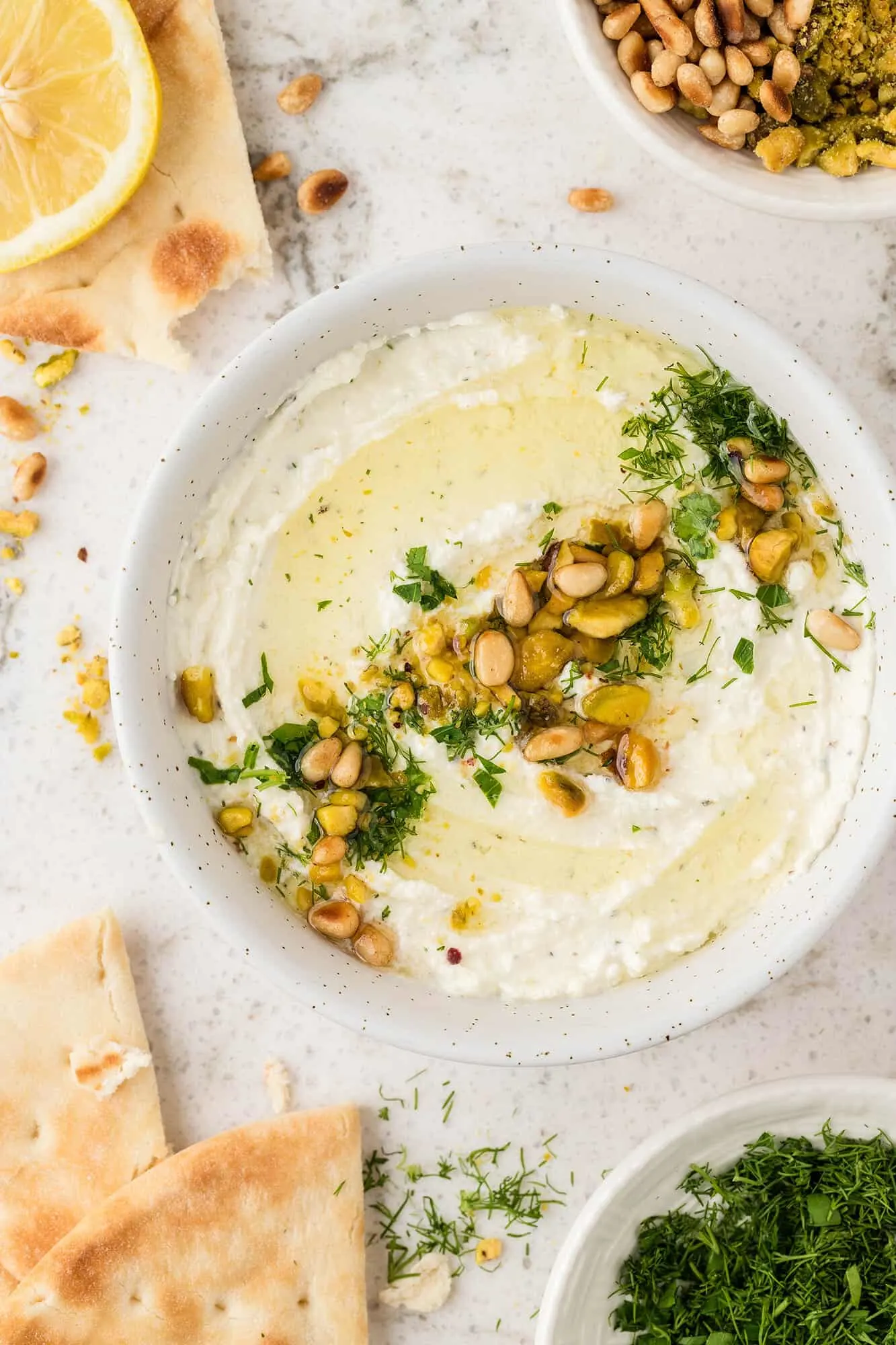whipped greek feta dip in a white bowl with garnishes and pita chips