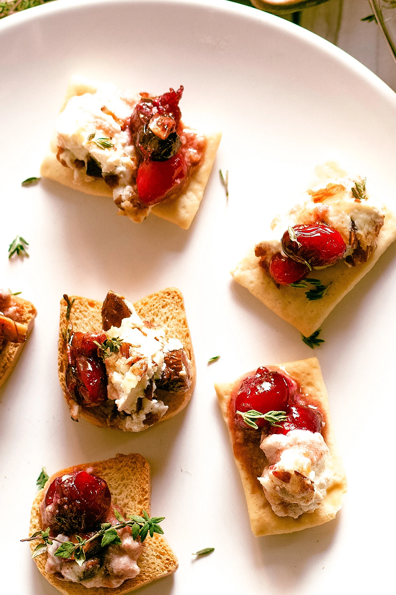 close up photo of baked goat cheese roasted cranberry appetizer on crackers - cranberry goat cheese crostini