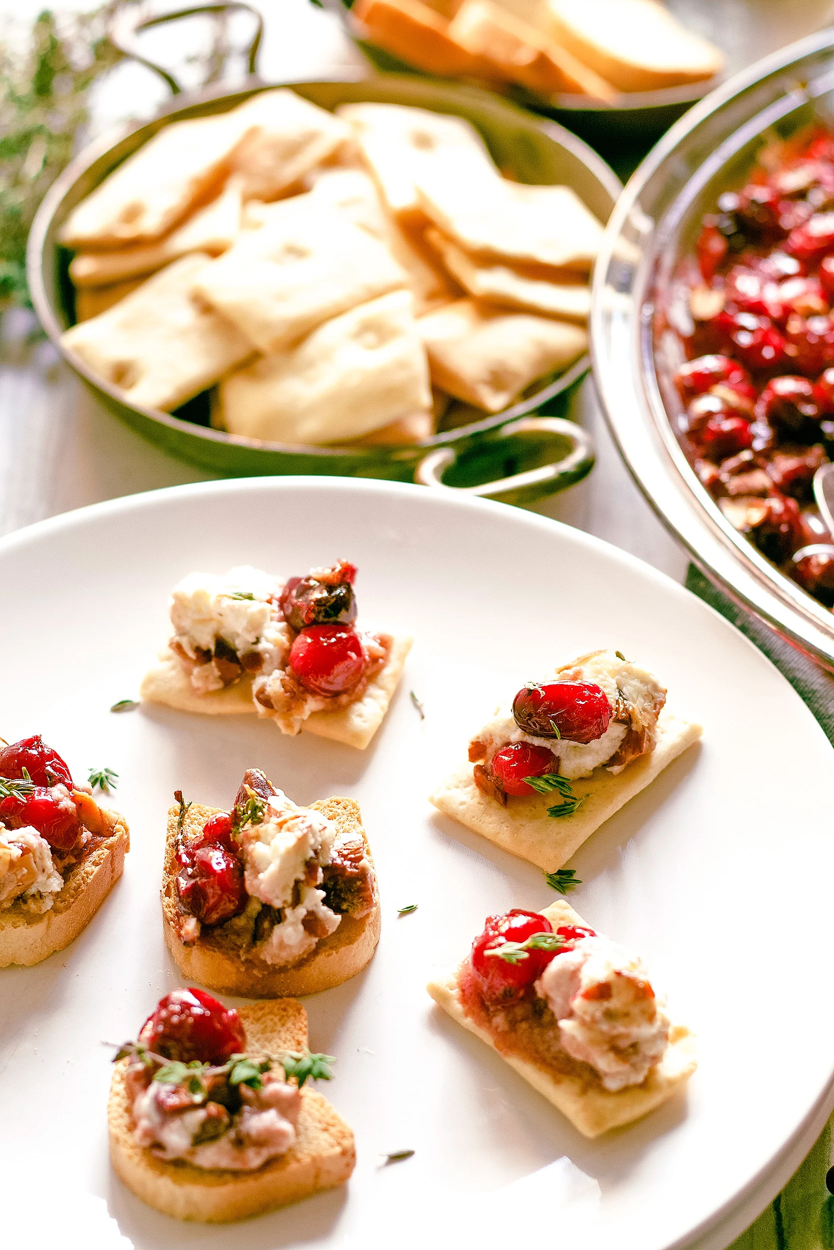 crackers in a bowl and topped with roasted cranberries and baked goat cheese