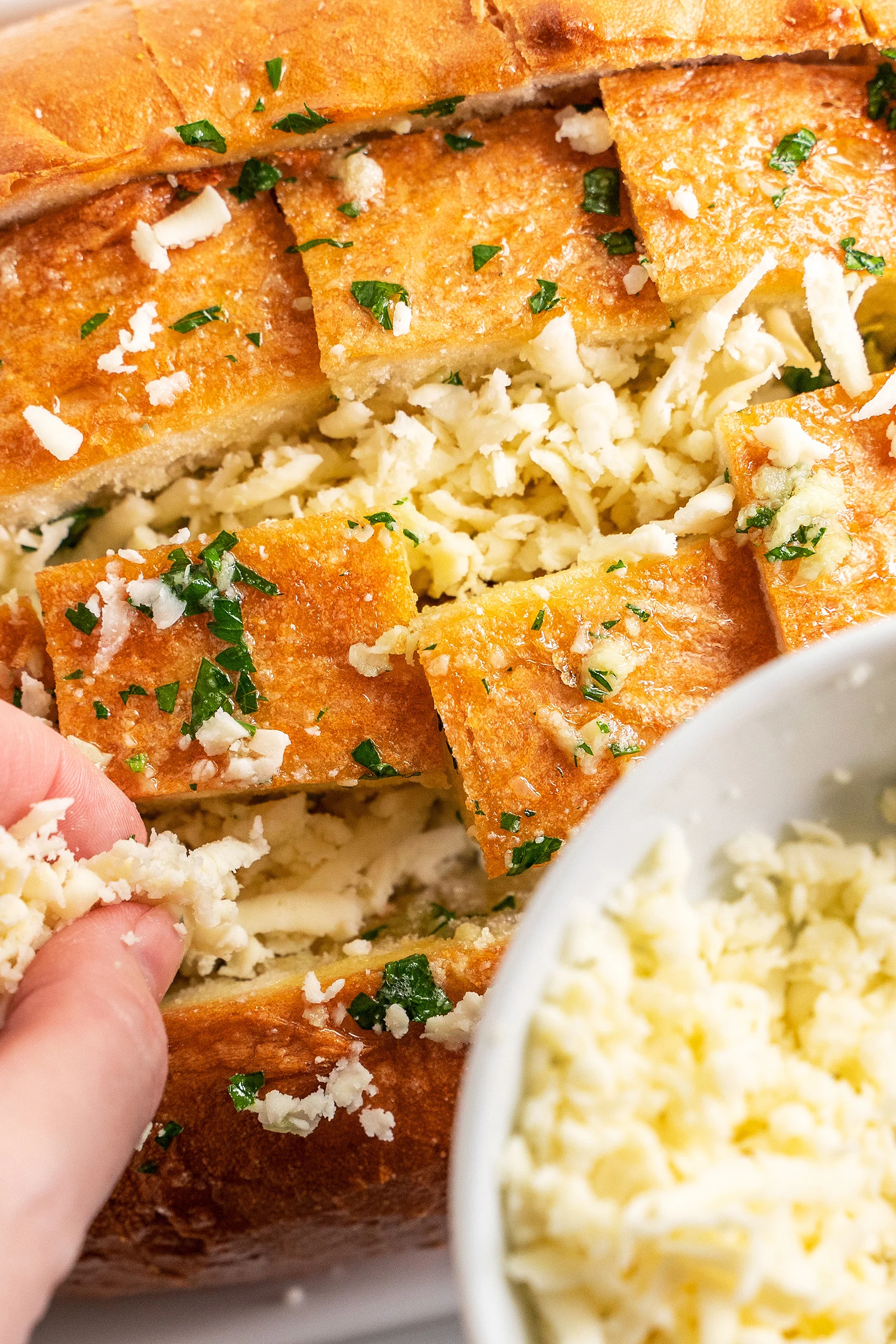 shredded mozzarella cheese being stuffed in between the bread chunks