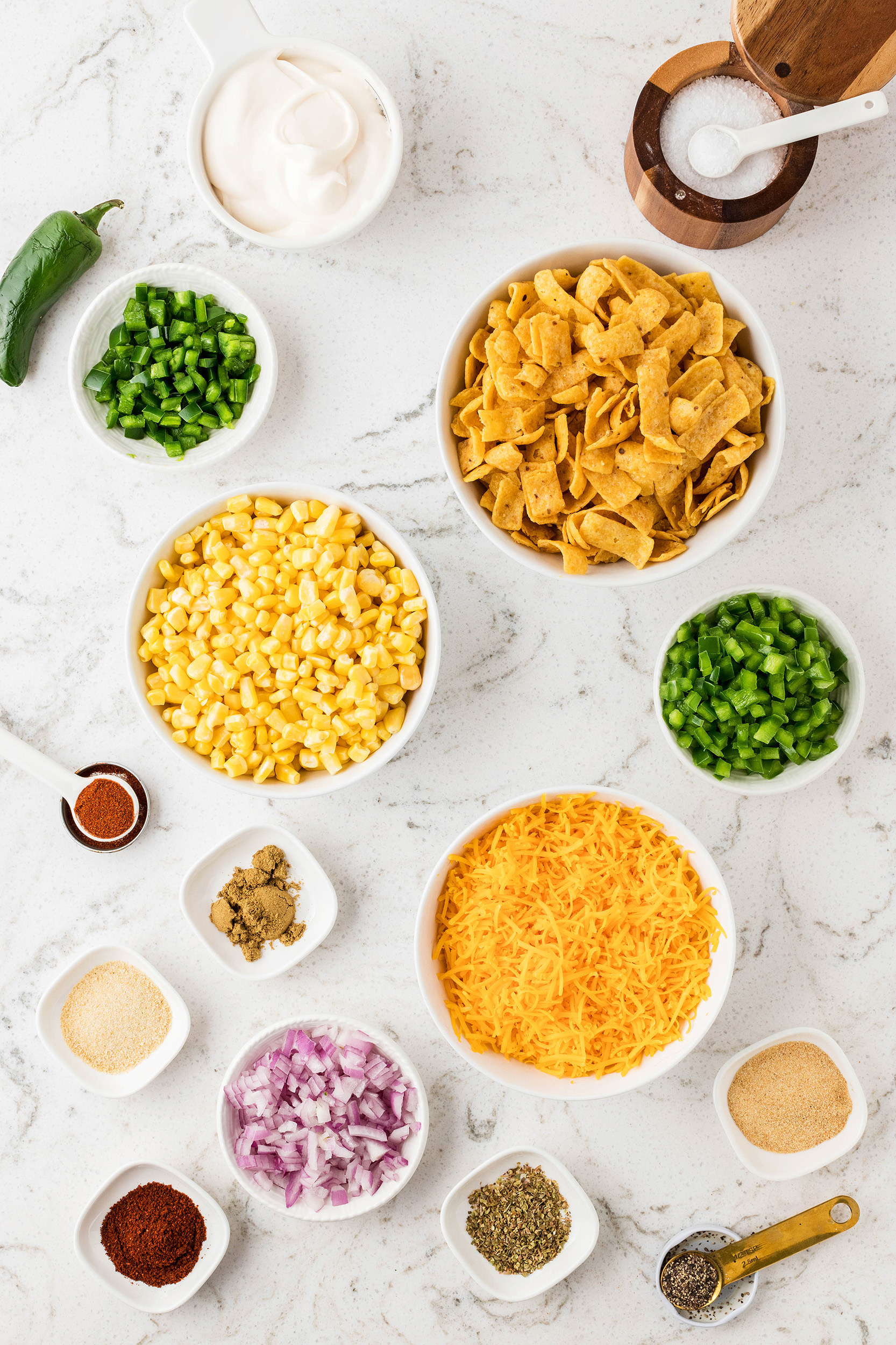 frito corn salad ingredients in small bowls on a marble countertop