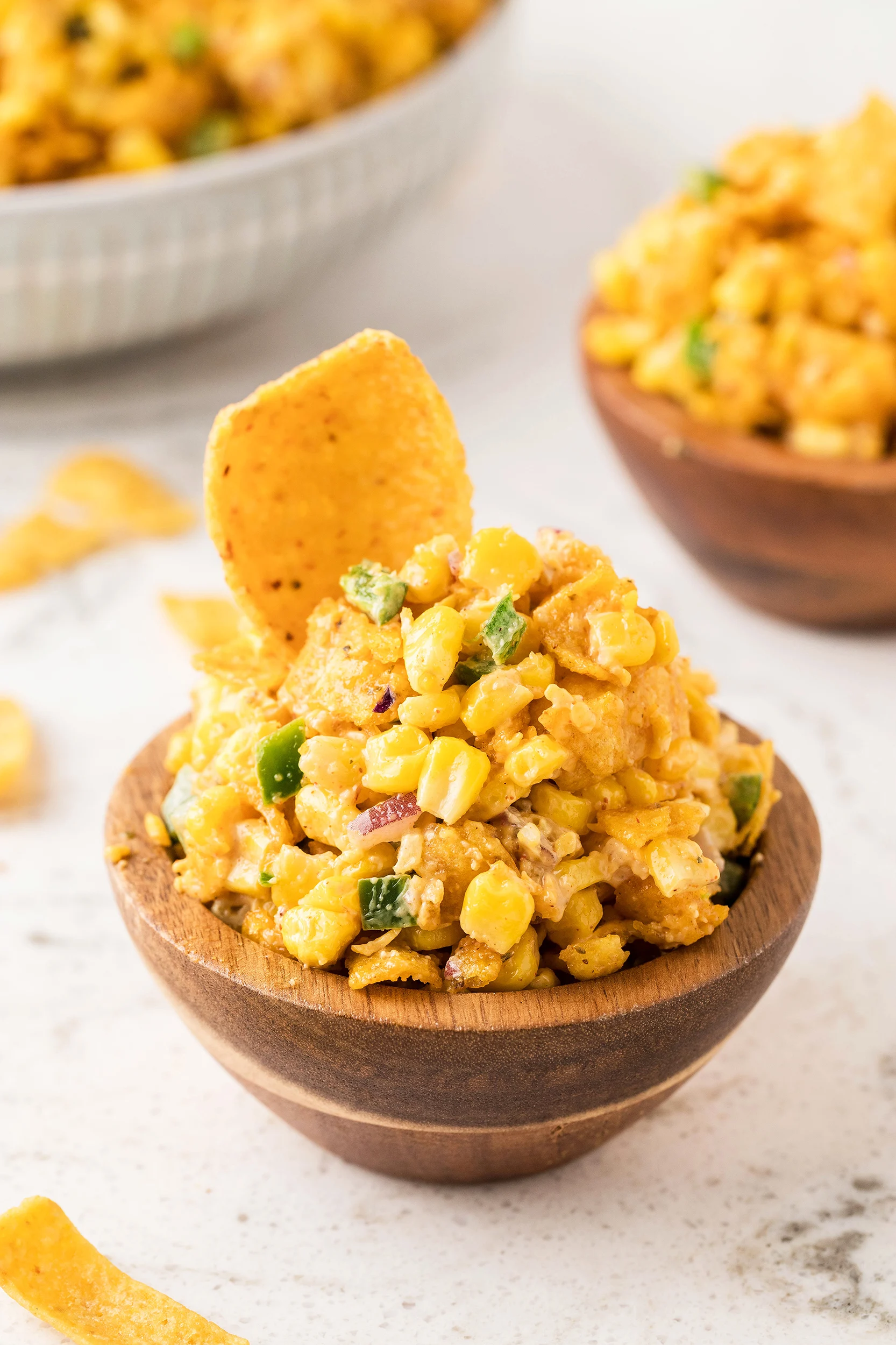 wooden bowl full of corn salad with a frito on top