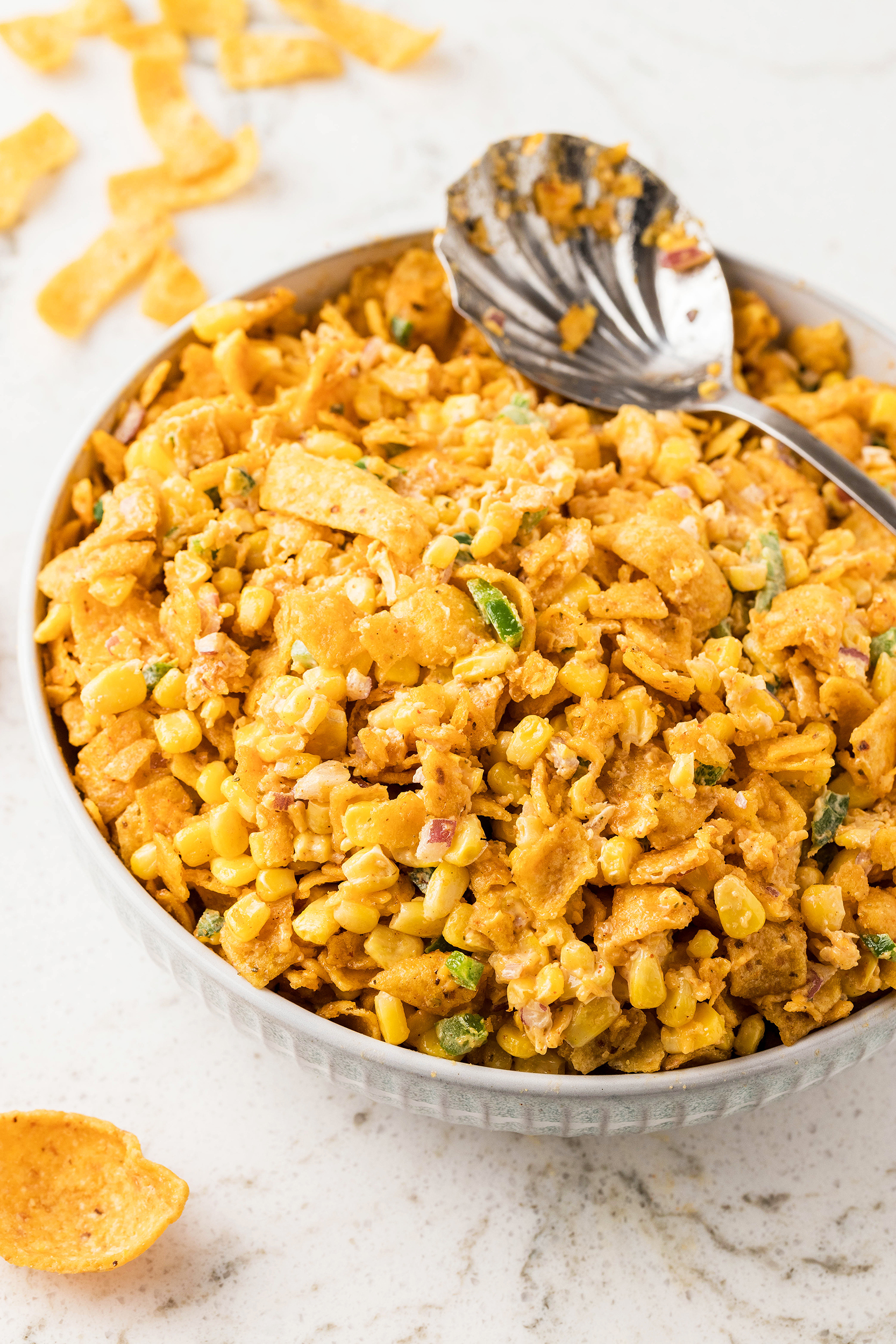 bowl of frito corn salad with a large metal serving spoon on top