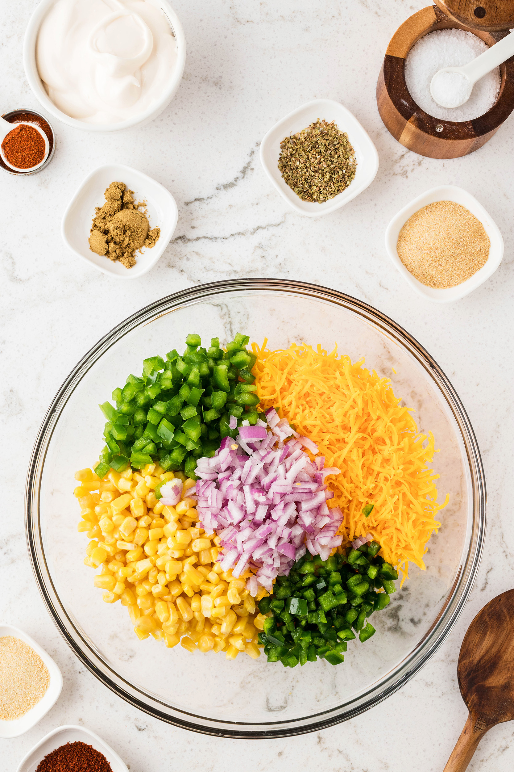 frito salad vegetable ingredients and cheddar cheese in a glass mixing bowl