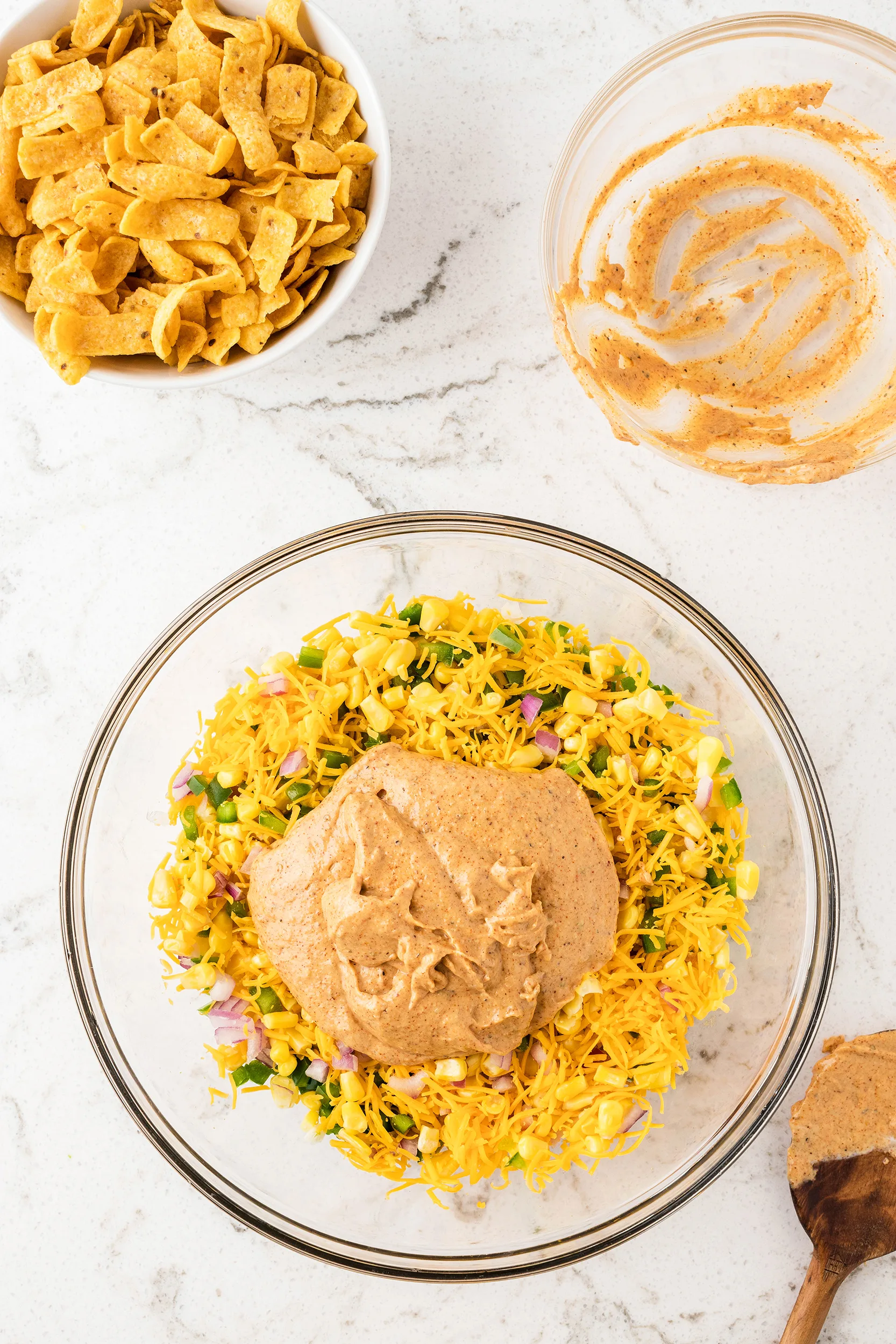 frito corn salad with the sauce pre-mixing in a glass bowl
