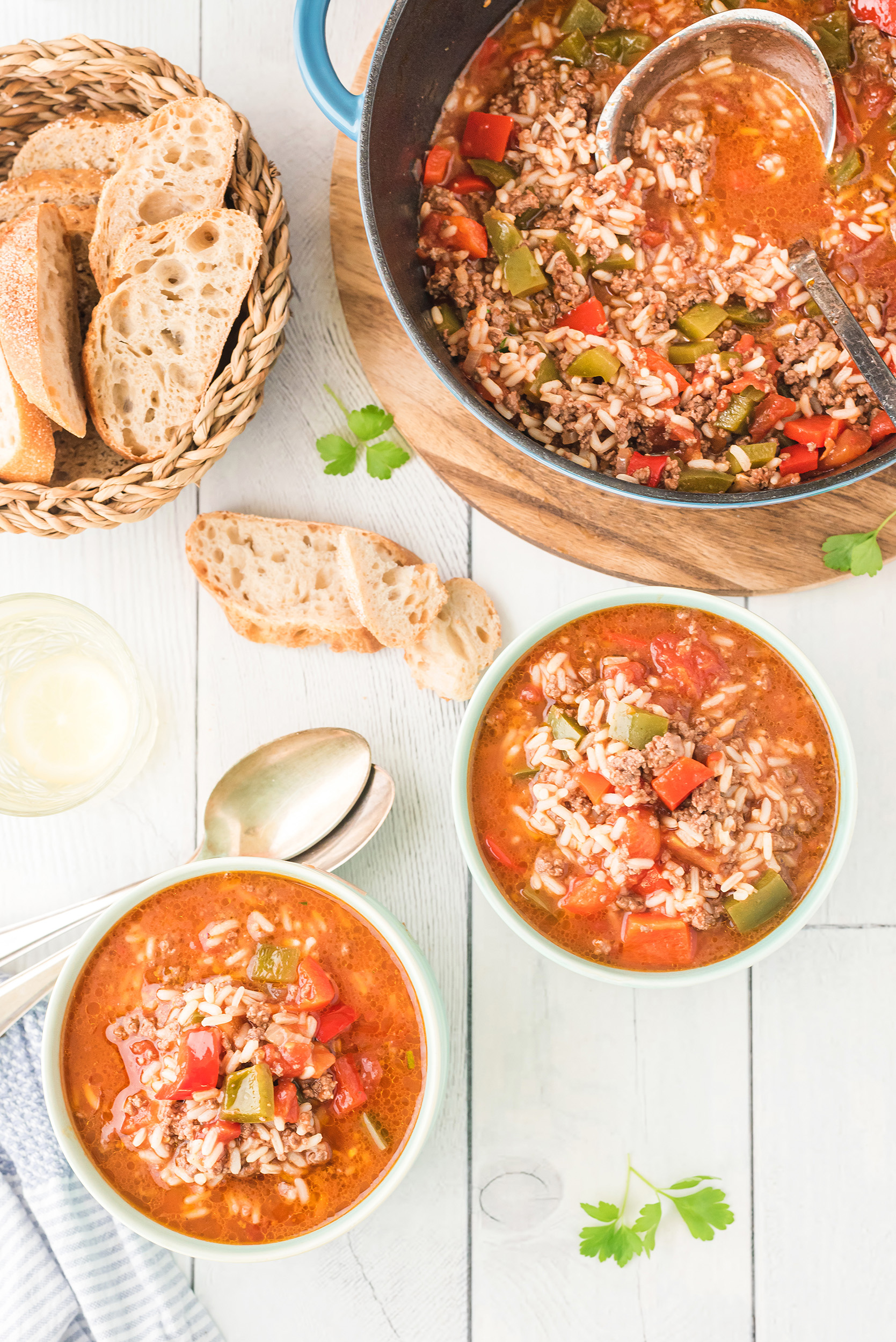 two bowls of stuffed pepper soup with crusty bread on the side. The large soup pot is in the background