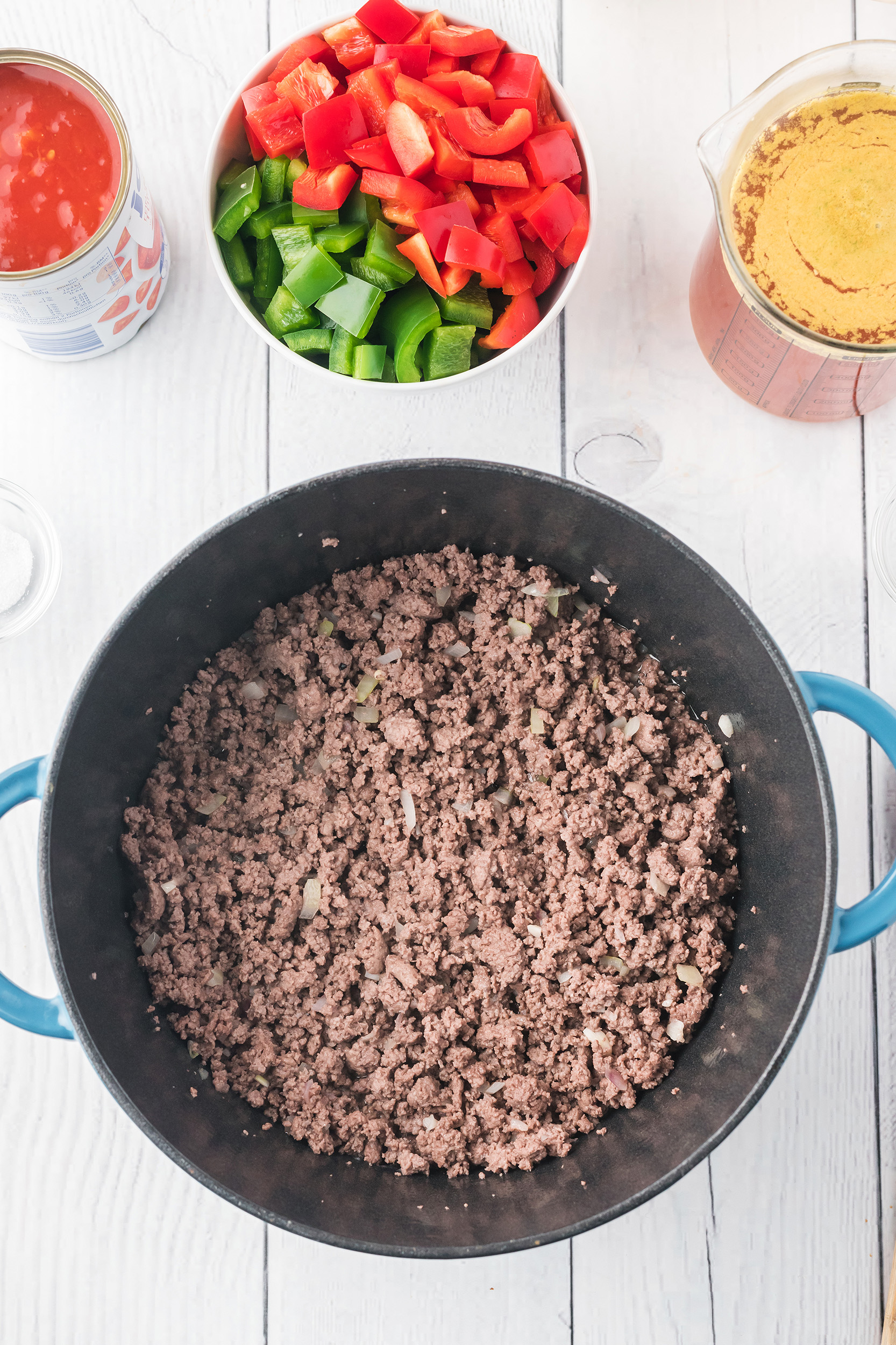 sautéed ground beef, onions and garlic in a Dutch oven on a white board