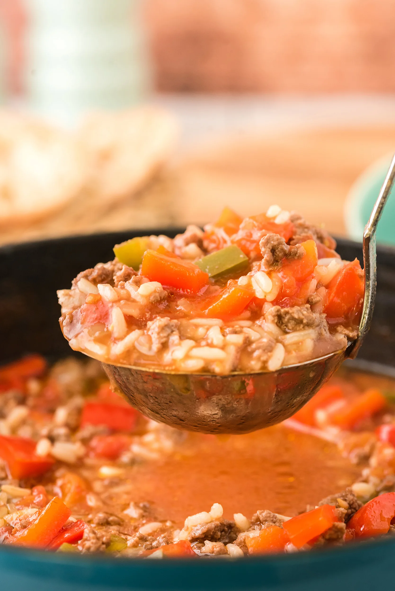 closeup shot of a ladle full of soup, with a wooden background