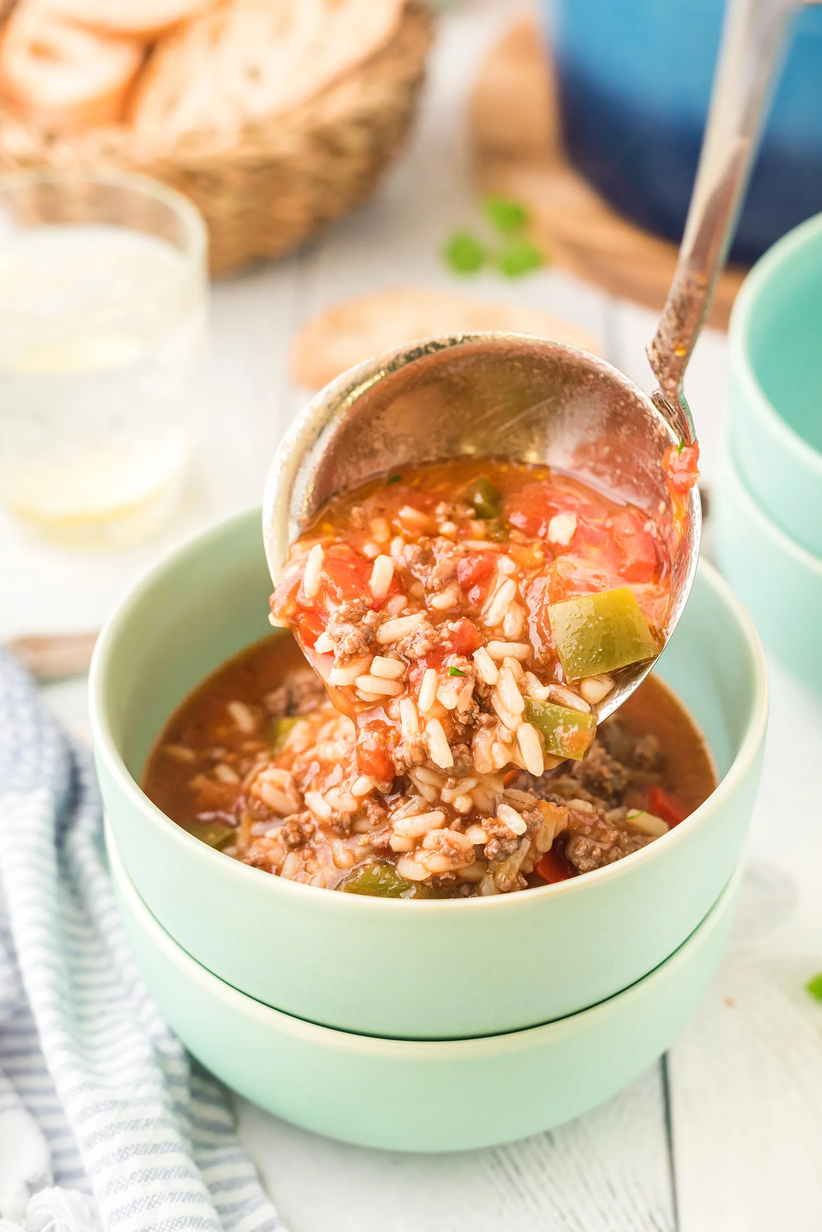 stuffed pepper soup being ladled into a mint green bowl