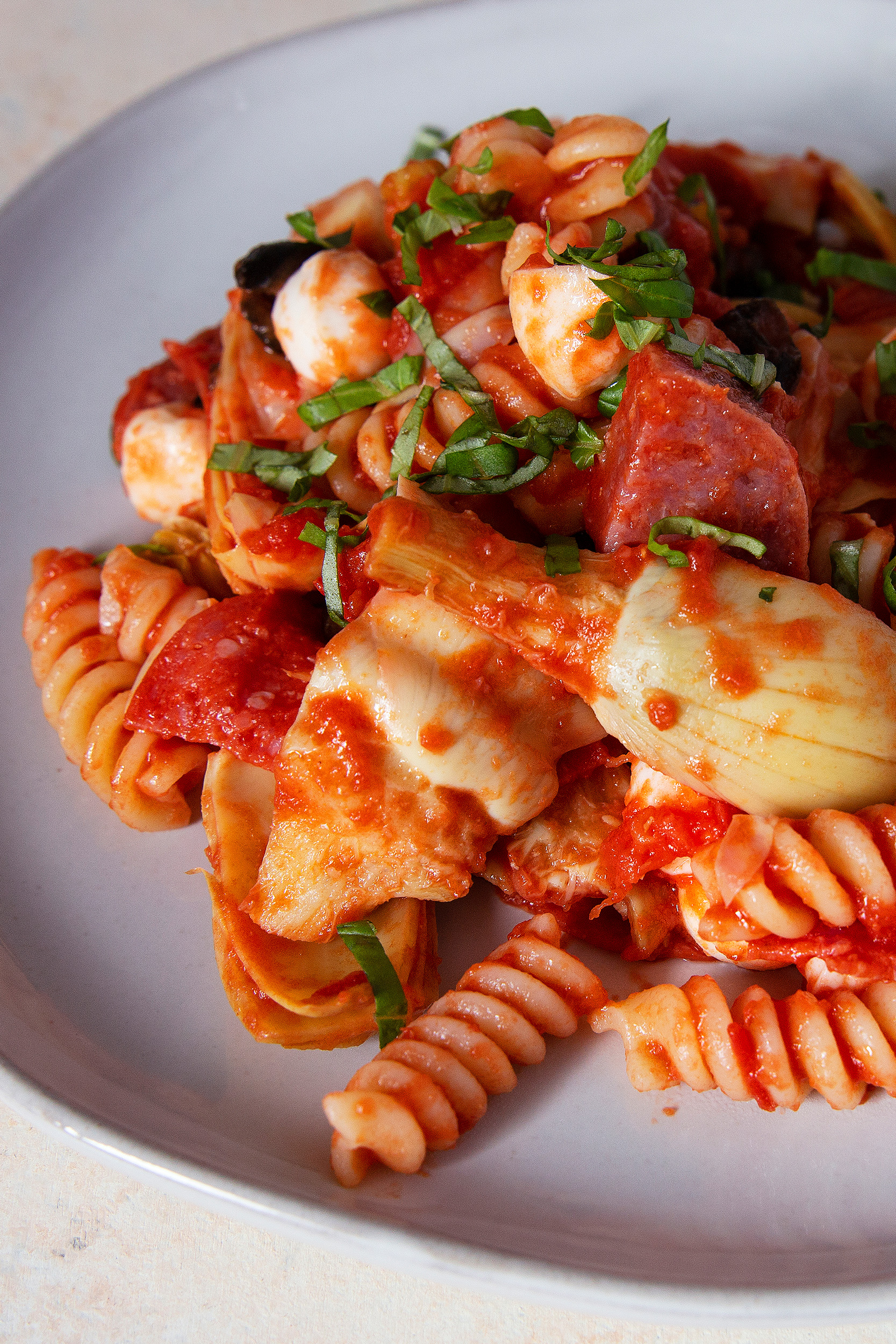 a big helping of antipasto pasta on a grey plate