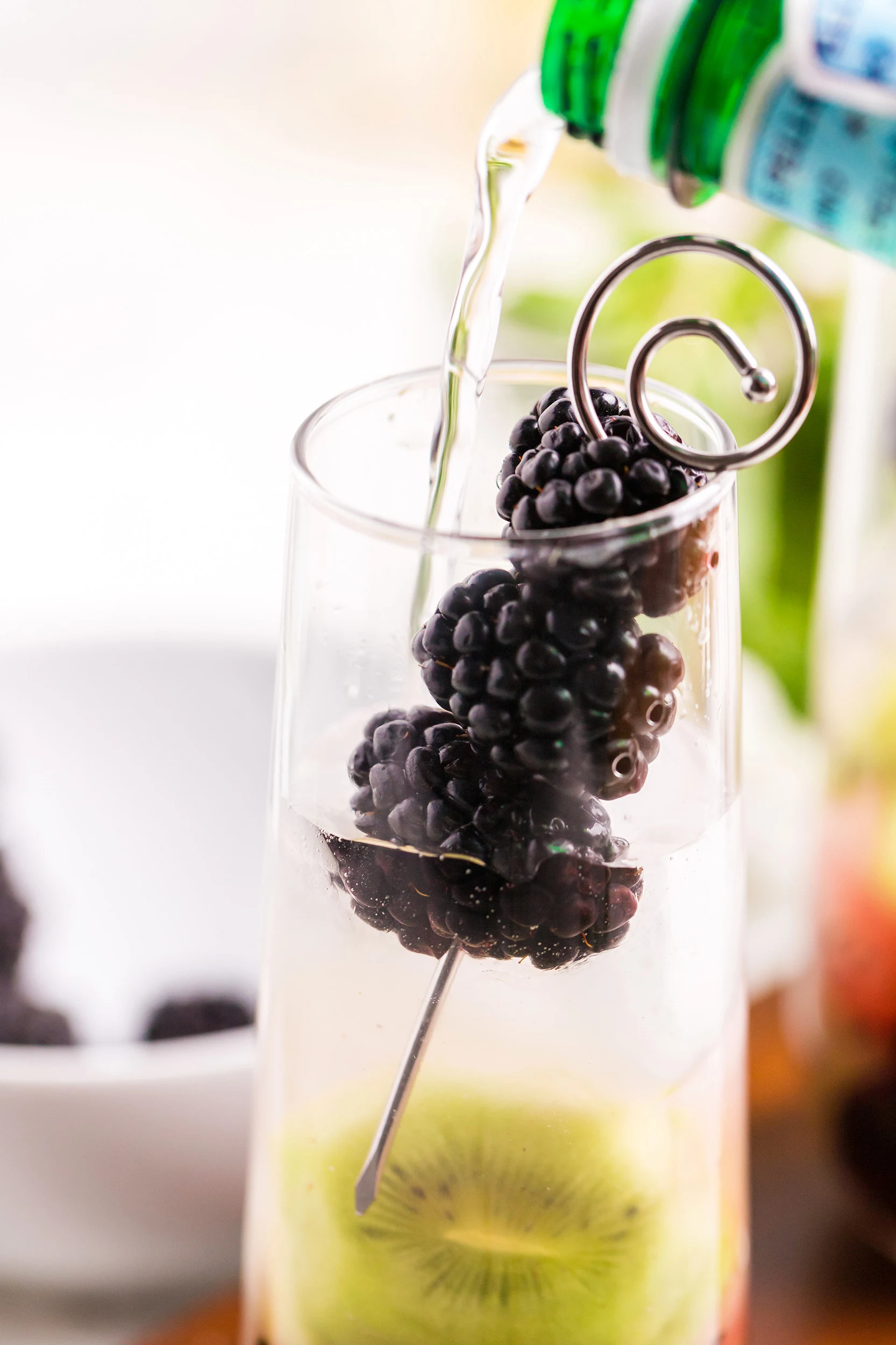adding soda water, the final touch, to the blackberry kiwi mojito