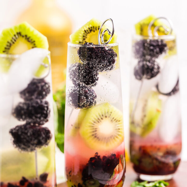 blackberry kiwi mojito recipe garnished with a cocktail pick of blackberries and a kiwi round