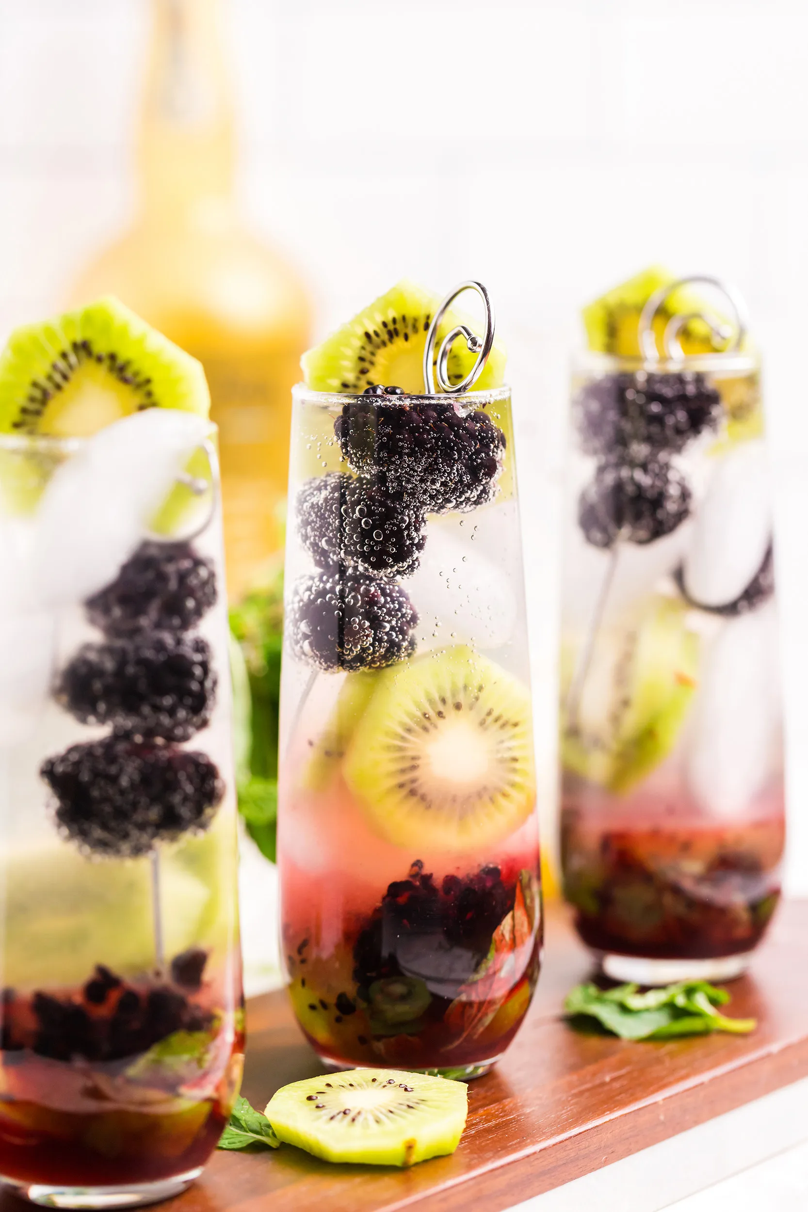 blackberry kiwi mojito recipe garnished with a cocktail pick of blackberries and a kiwi round