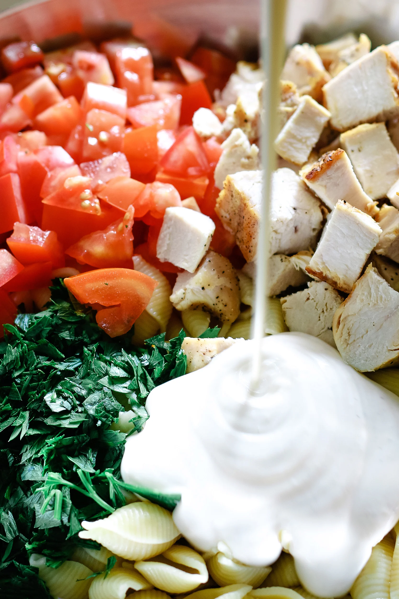 ranch dressing poured on top of other ingredients for ranch chicken pasta salad