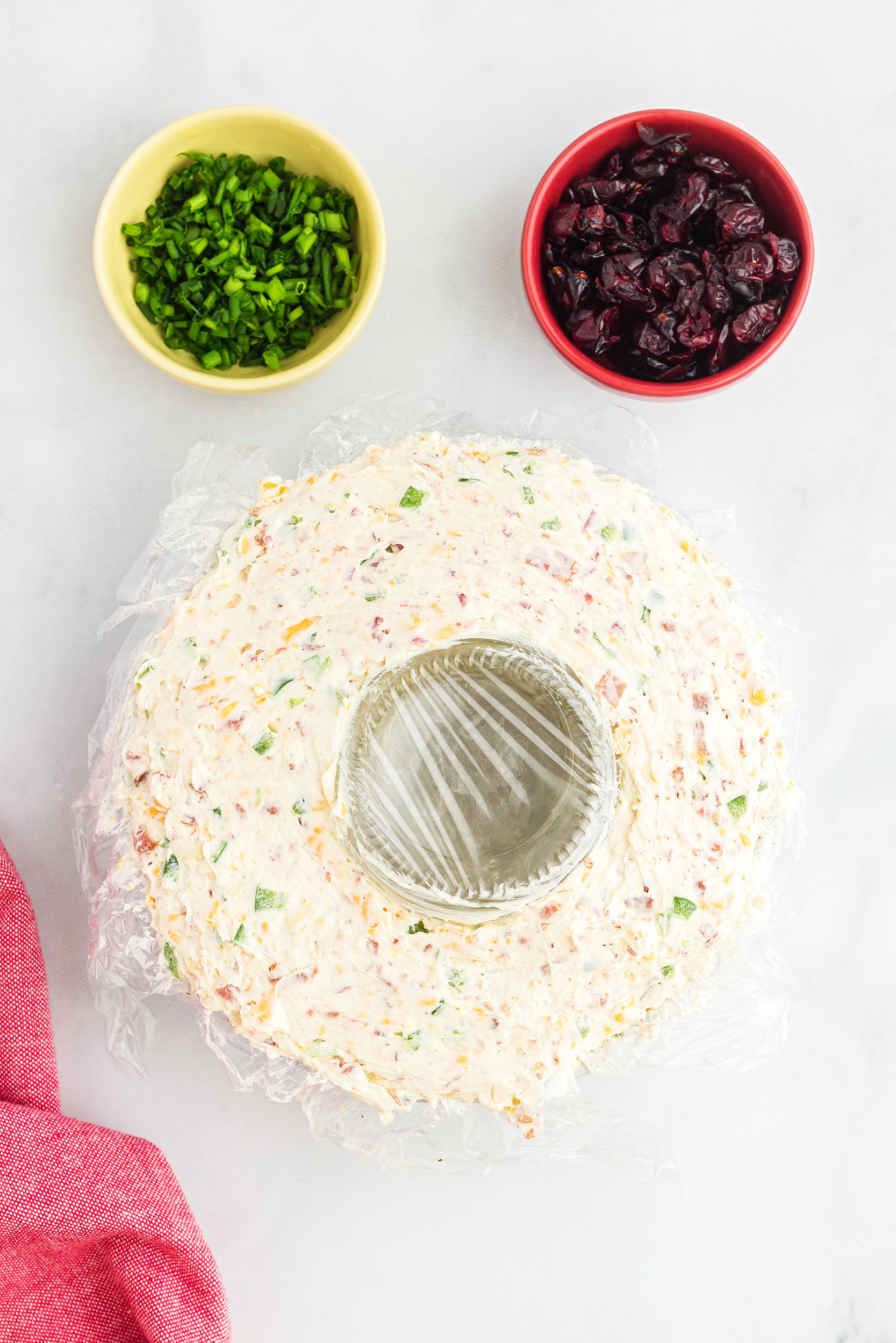 prepared Christmas wreath cheese ball recipe covered in plastic wrap