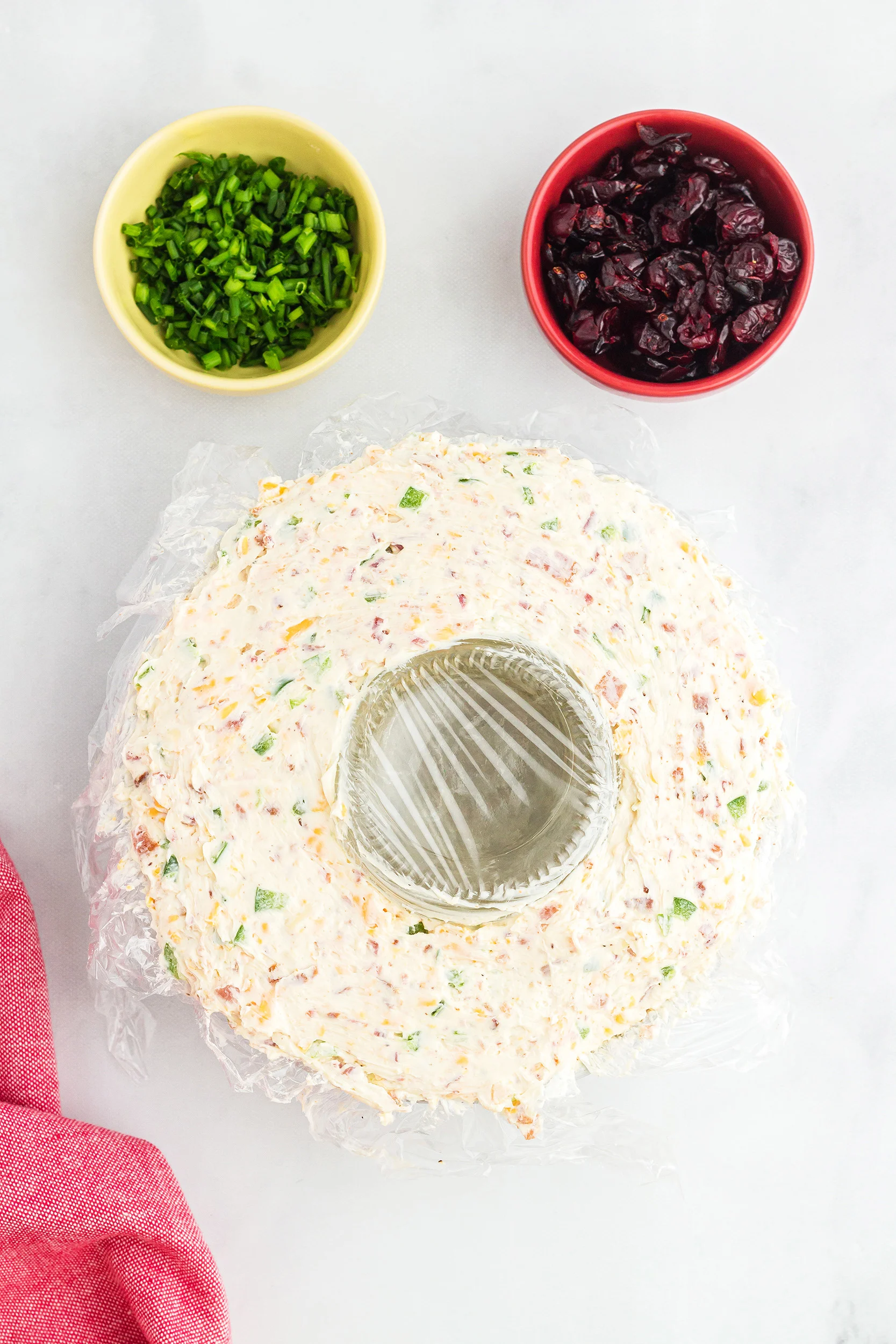 prepared Christmas wreath cheese ball recipe covered in plastic wrap