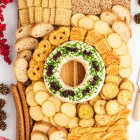 large charcuterie board with a festive Christmas cheese ball in the center surrounded by an assortment of crackers