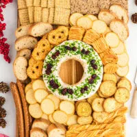 large charcuterie board with a festive Christmas cheese ball in the center surrounded by an assortment of crackers