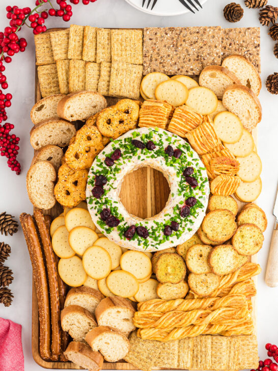 large charcuterie board with a festive Christmas cheese ball in the center surrounded by an assortment of crackers