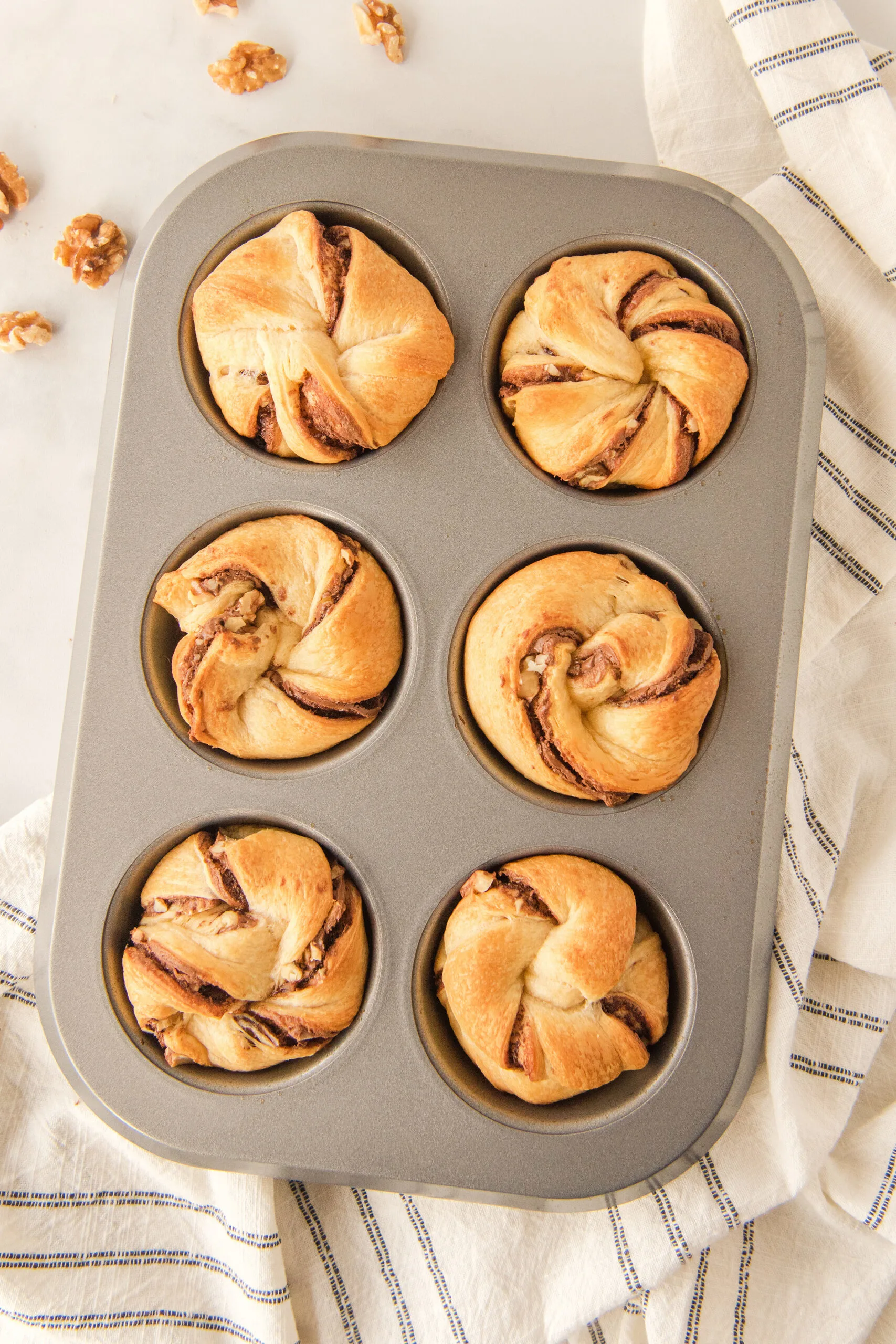 golden brown Nutella muffins in a large muffin tin