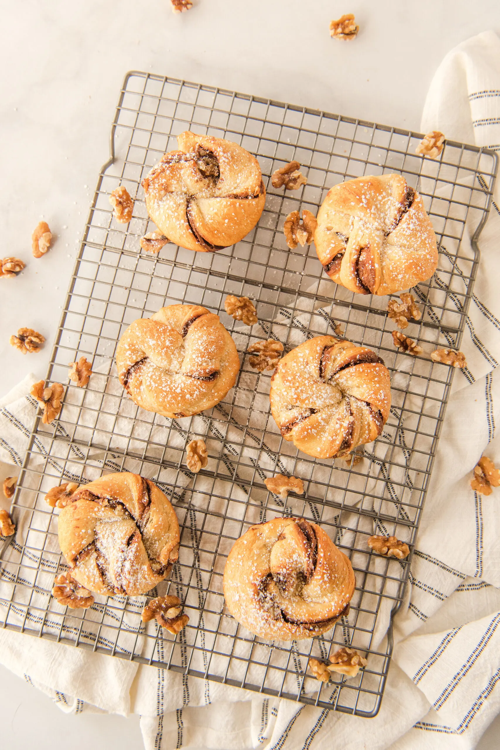 6 nutella muffins with confectioners' sugar on a wire rack with a cloth napkin