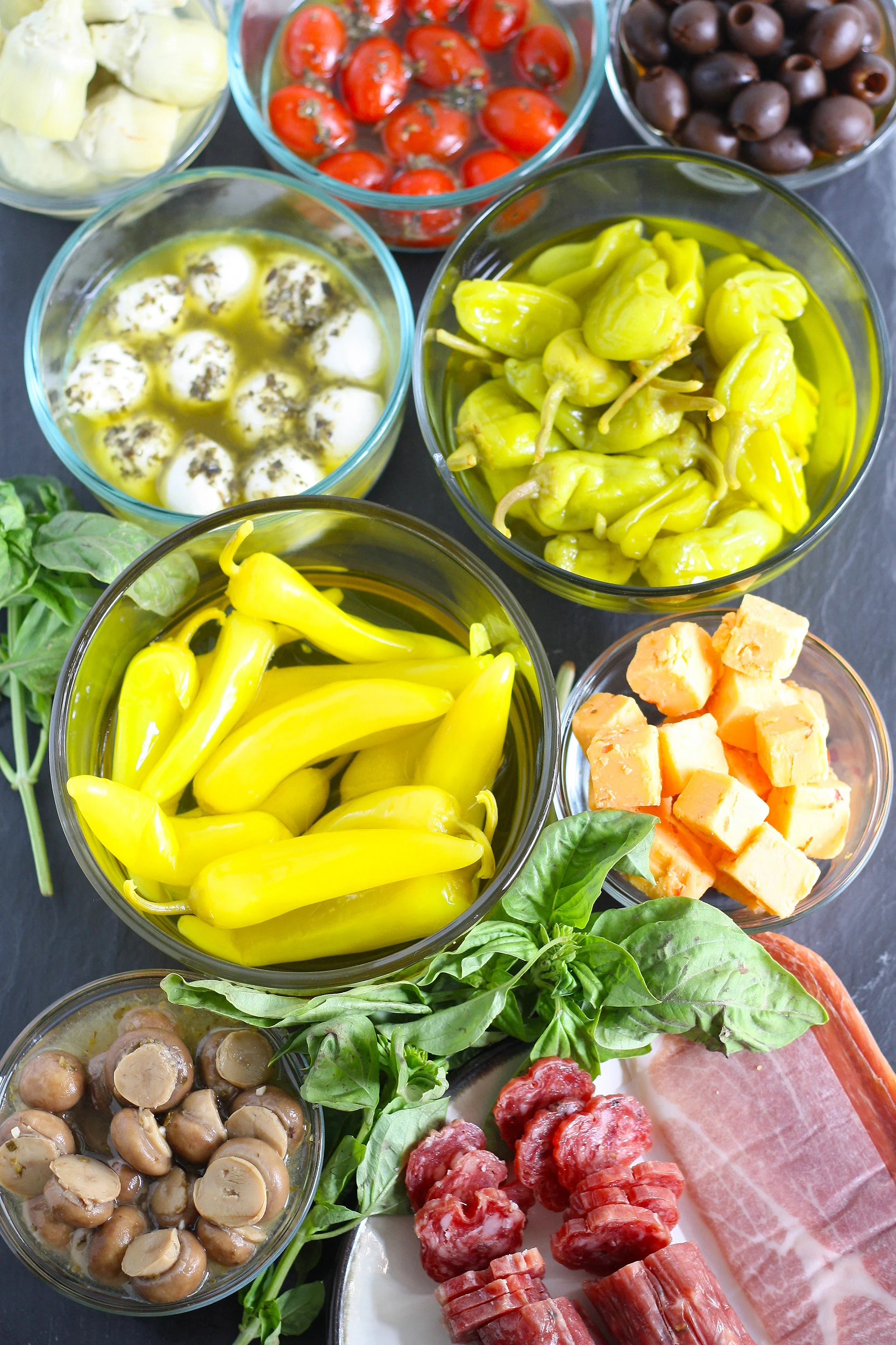 antipasto ingredients in glass bowls and on plates