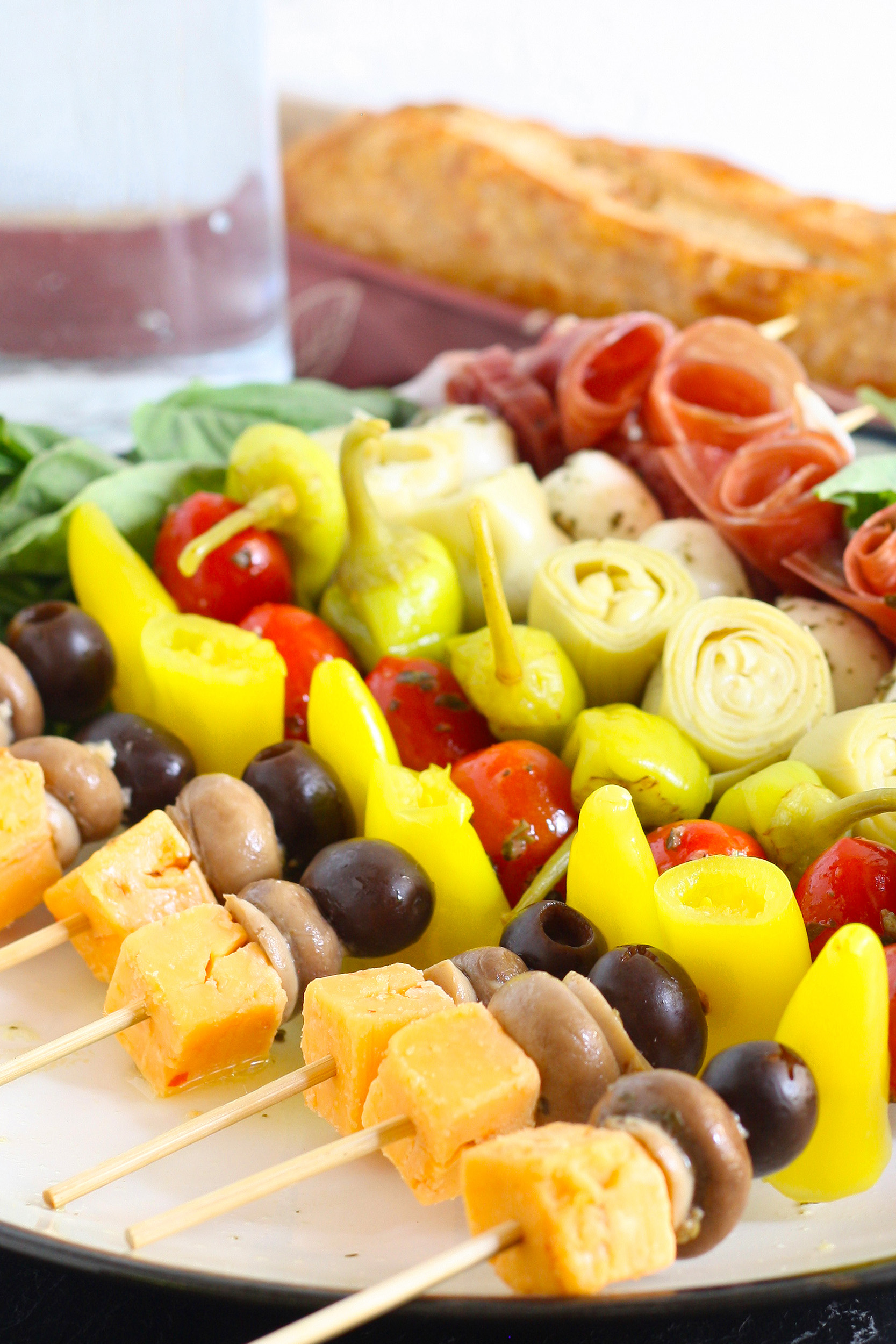 antipasto skewers on a plate with a loaf of bread and carafe of water