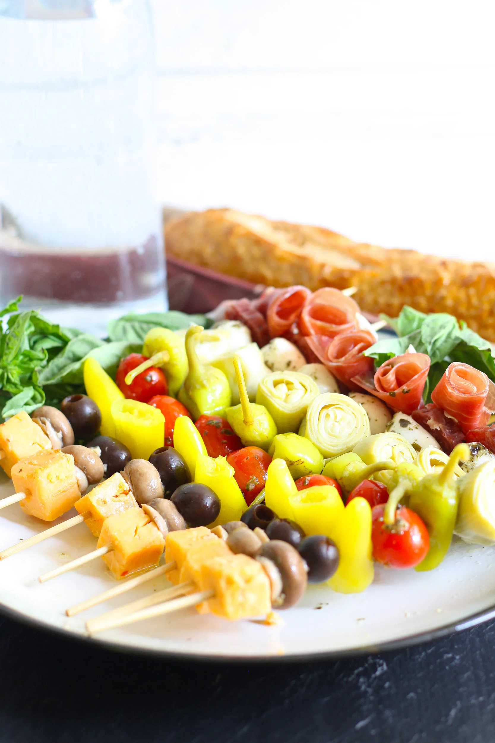 antipasto skewers ready to be served on a white plate with a black rim
