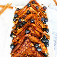 plate of cinnamon French toast topped with nuts, blueberries and maple syrup