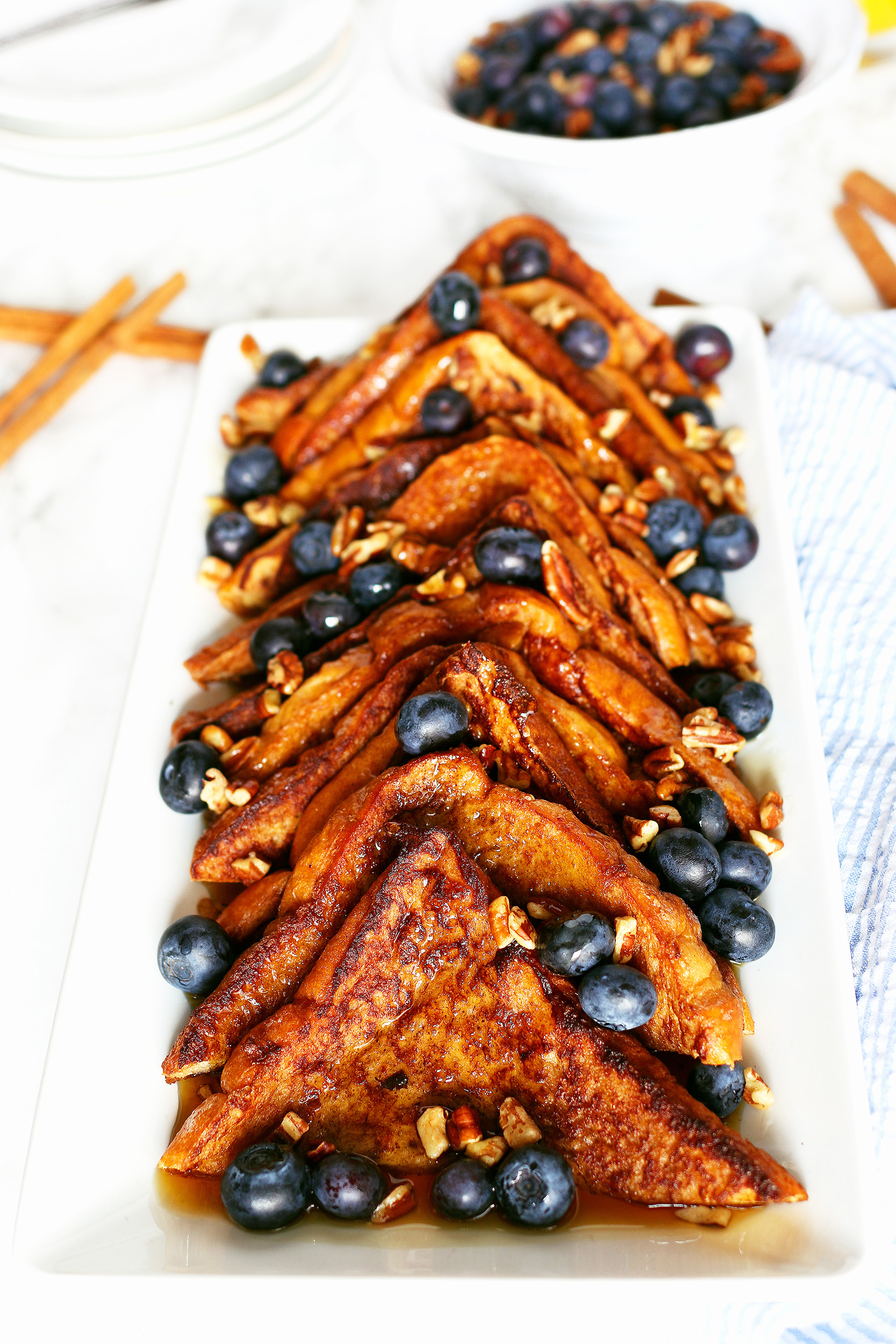 plate of cinnamon French toast topped with nuts, blueberries and maple syrup