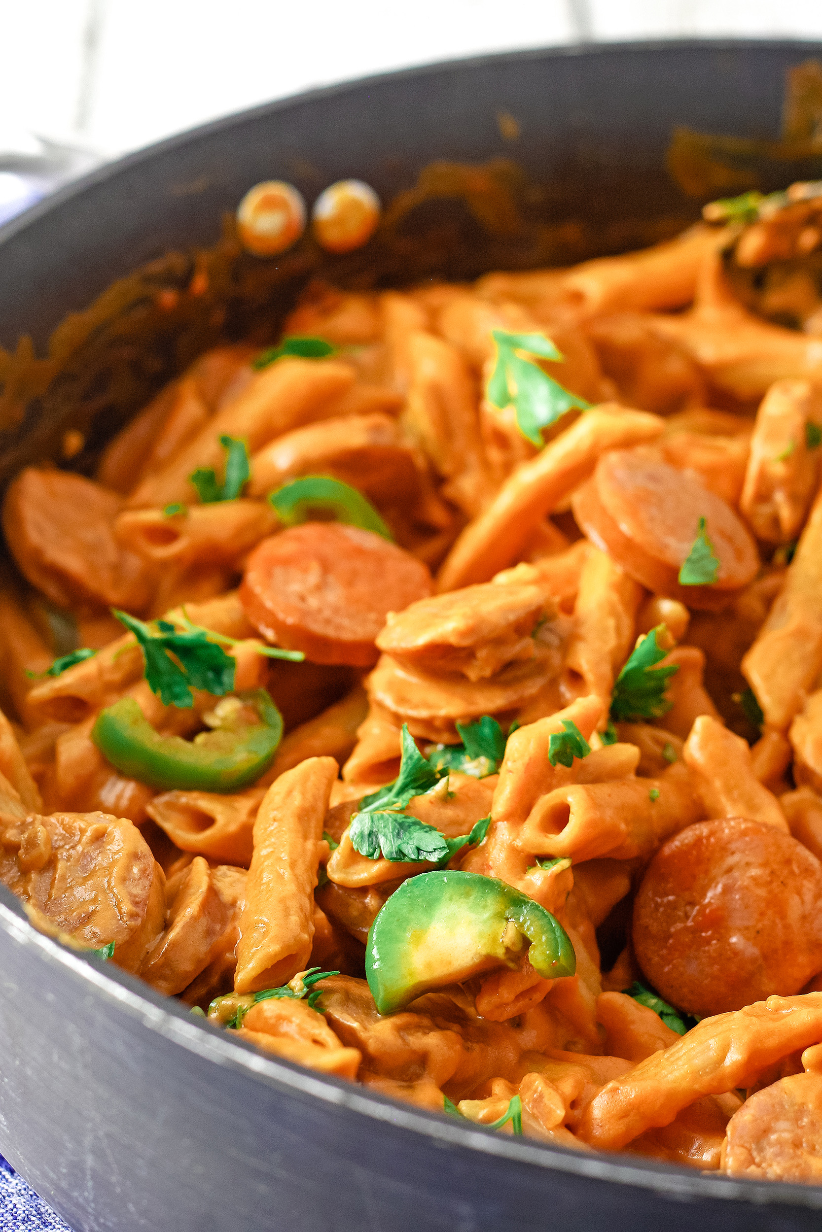 spicy sausage pasta cooking in a skillet