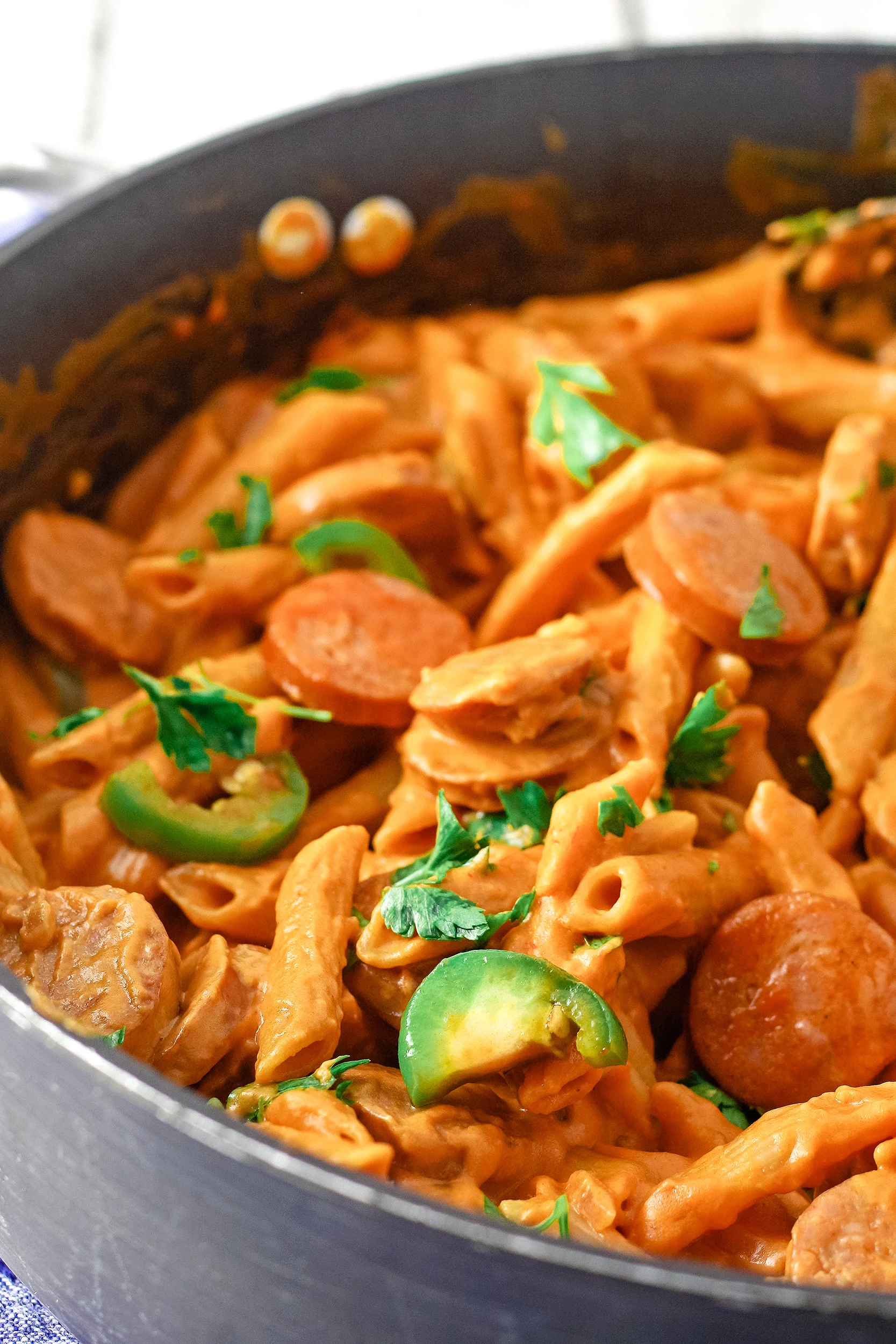 spicy sausage pasta cooking in a skillet