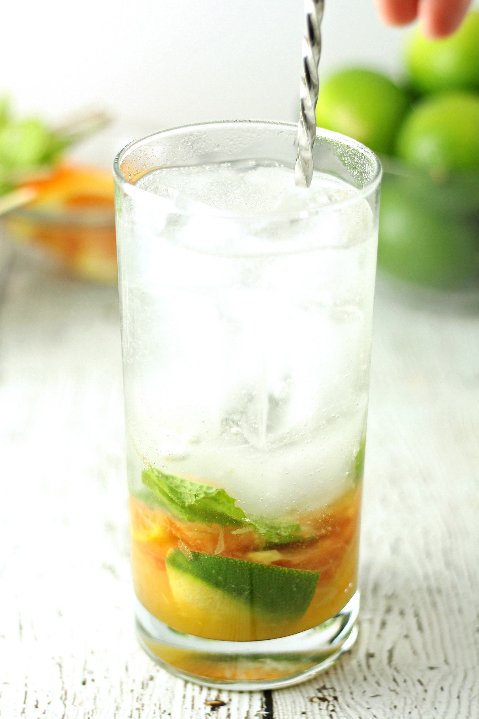 stirring mojito ingredients together in a collins glass