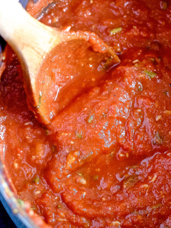 homemade roasted garlic tomato sauce in a pot being stirred with a wooden spoon