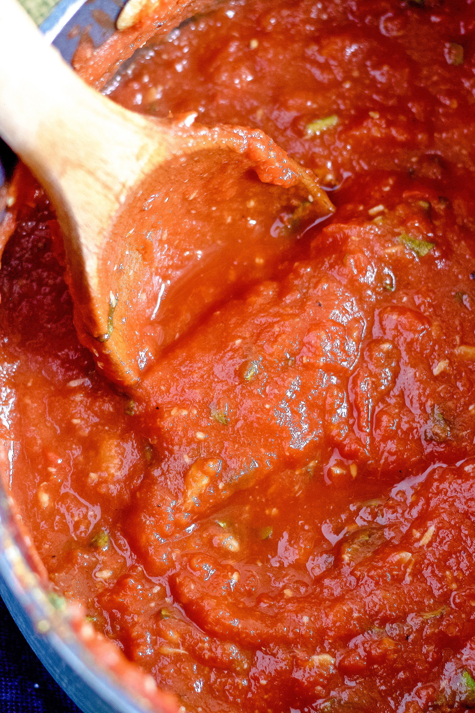 homemade roasted garlic tomato sauce in a pot being stirred with a wooden spoon