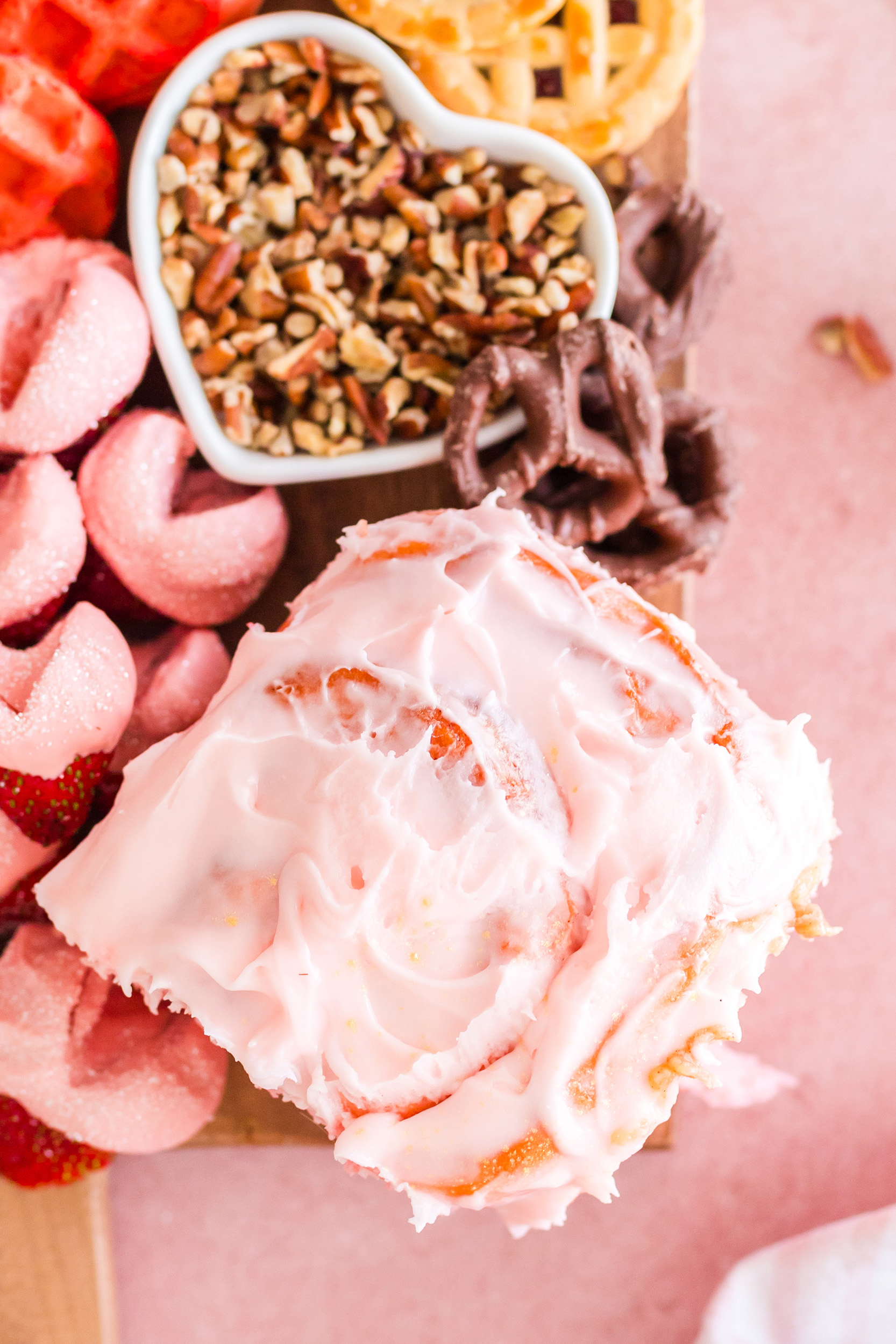 strawberry cinnamon roll on a board with other sweets and breakfast treats