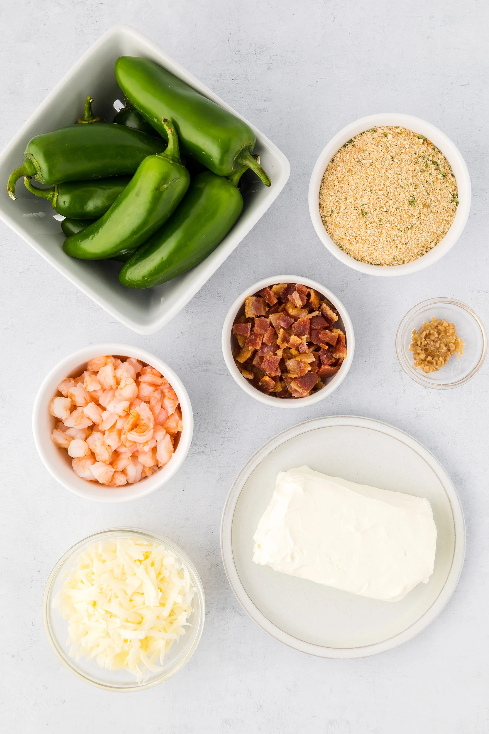 jalapeno peppers, bread crumbs, chopped shrimp, chopped bacon, shredded cheese, cream cheese, and garlic in small bowls