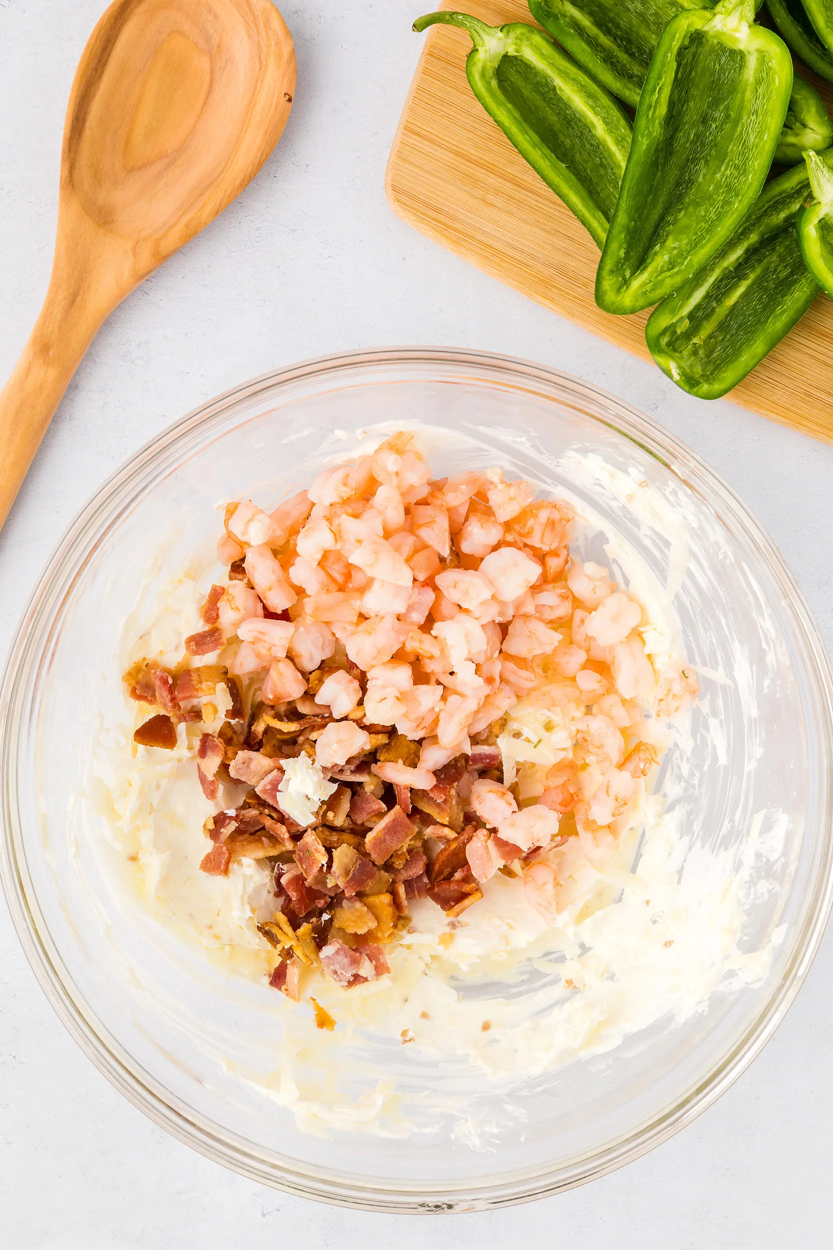 chopped shrimp and bacon added to cream cheese mixture in a glass bowl