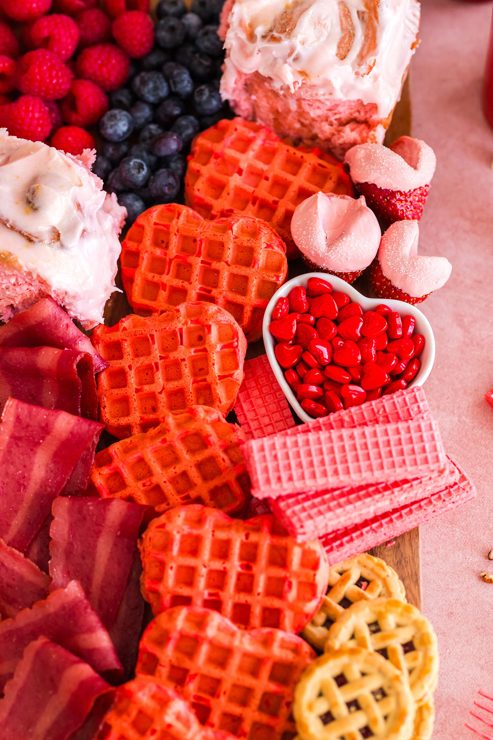 cândy hearts, pink wafer cookies and Lindzer cookies on a charcuterie board
