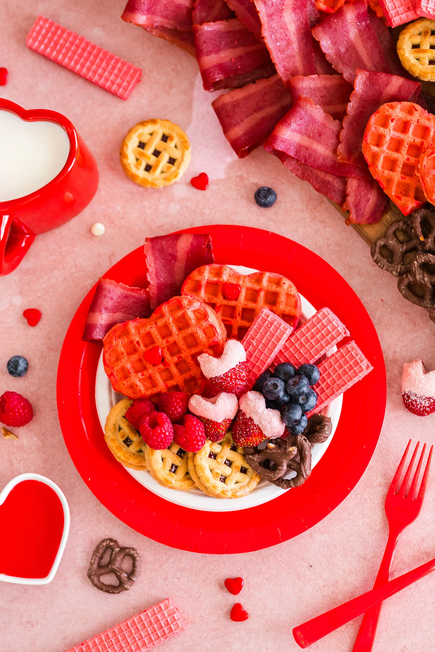 overhead photo of red plate with pink and red heart shaped items and fresh berries