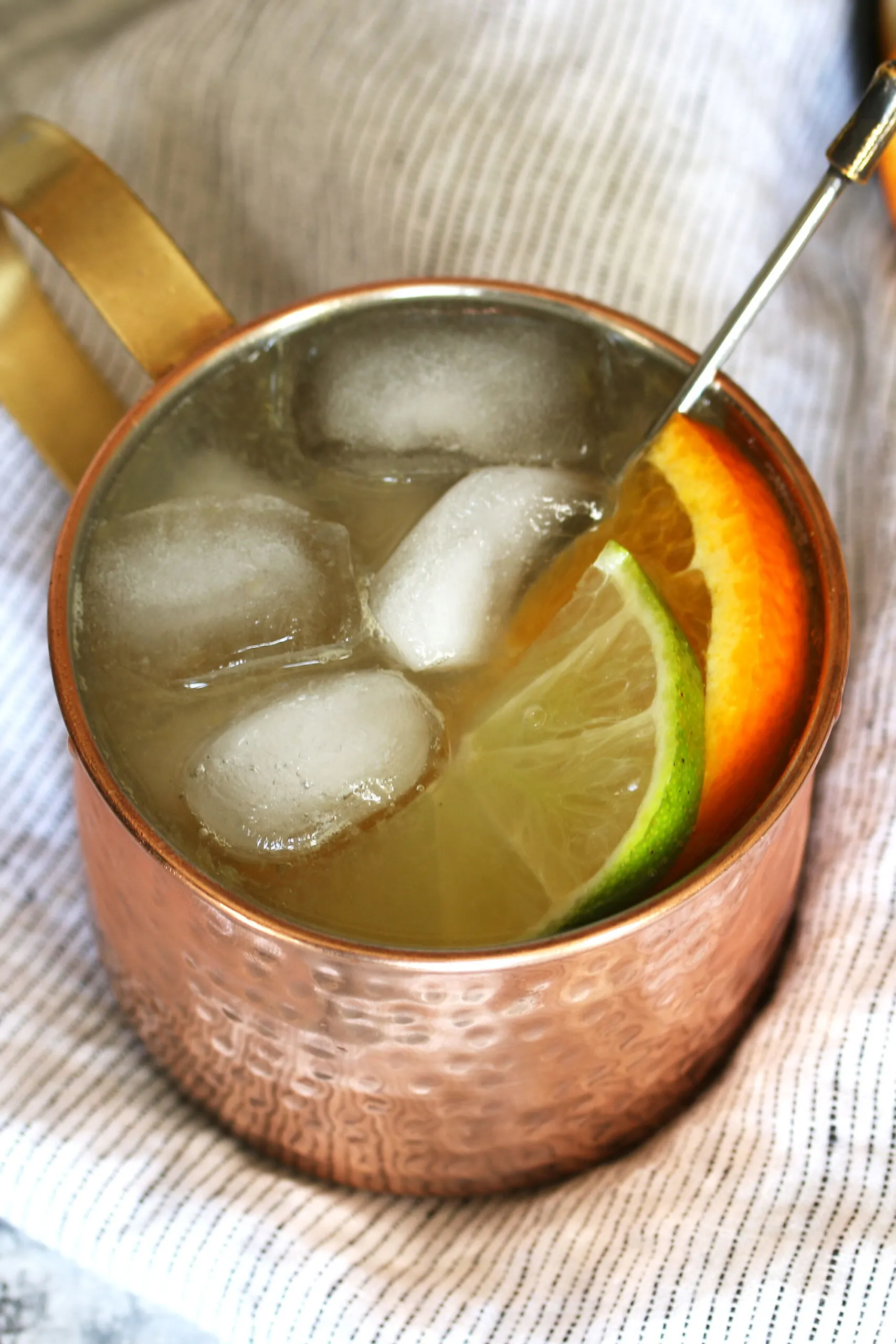 orange mule cocktail with ice, lime and orange garnishes