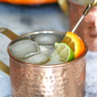 orange Moscow Mule garnished with a lime wedge and an orange slice
