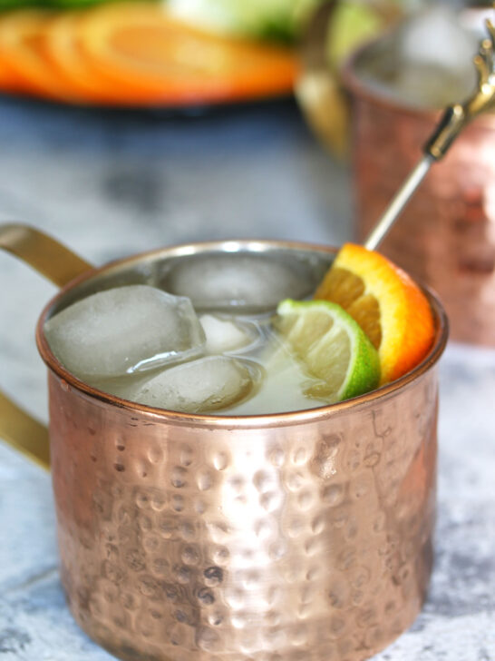 orange Moscow Mule garnished with a lime wedge and an orange slice