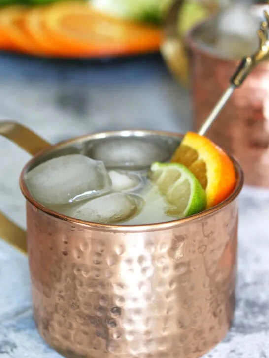 orange Moscow Mule garnished with a lime wedge and an orange slice