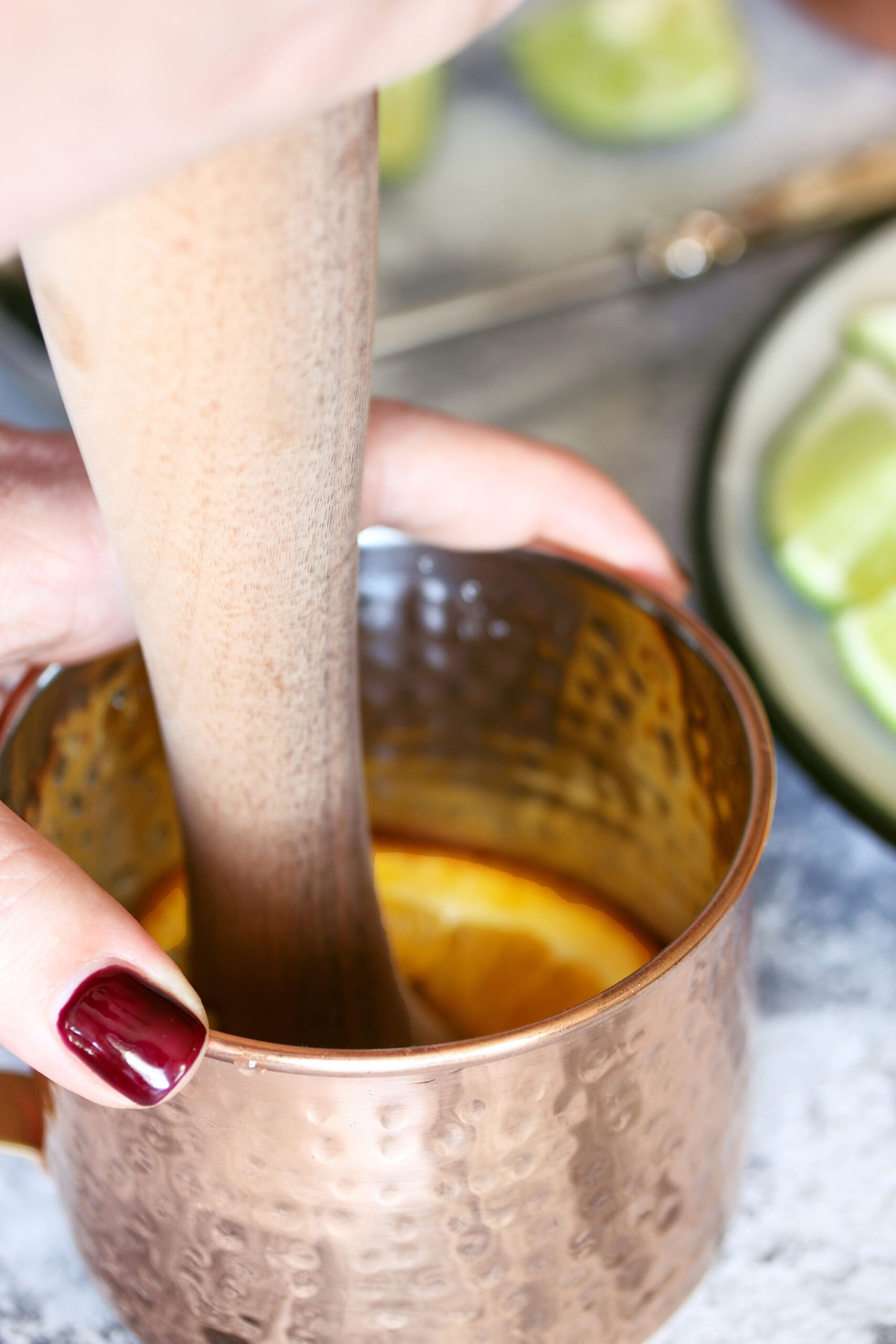 orange round being muddled in a Moscow Mule copper mug